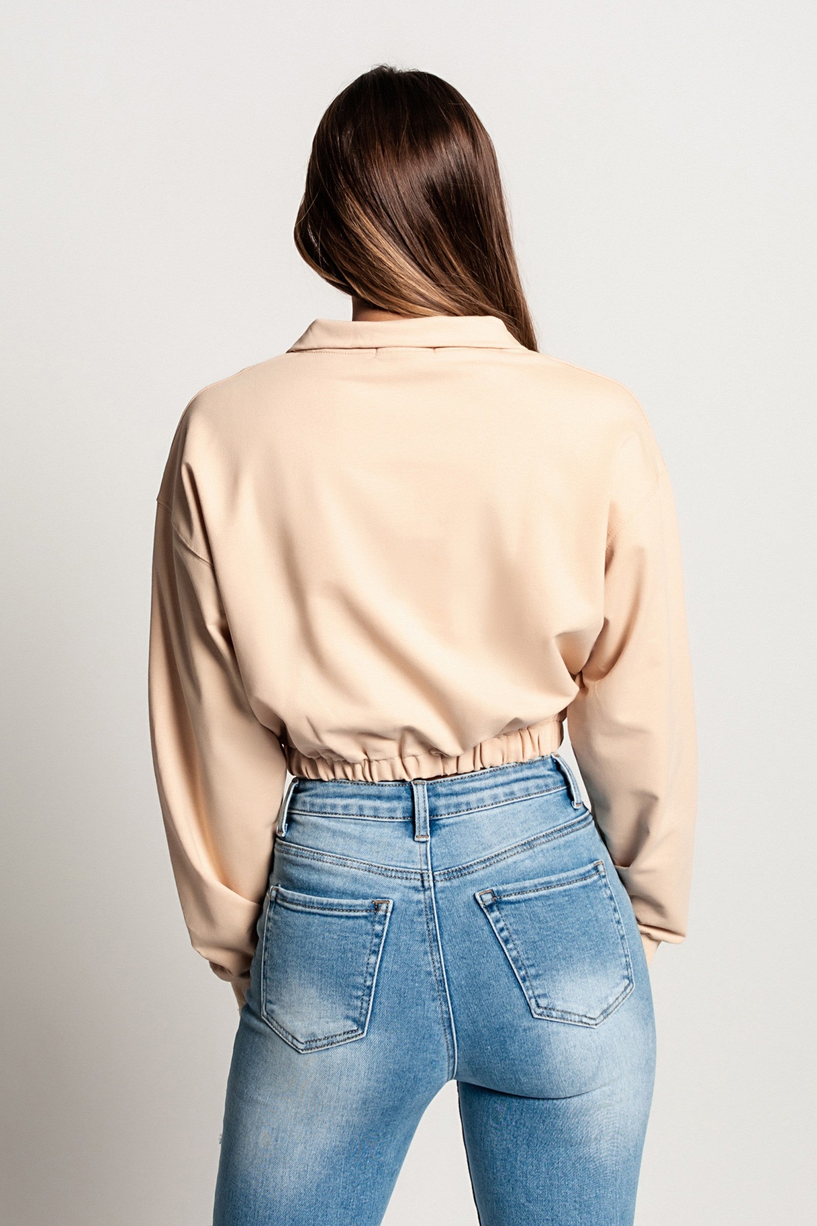 Skrajšana športna majica Polistena v bež barvi z dolgimi rokavi in visokim ovratnikom z zadrgo.